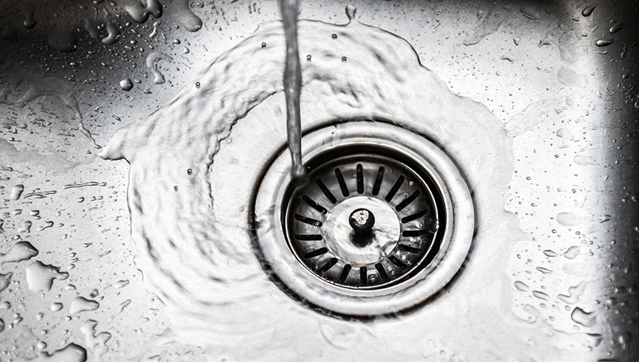 A stream of clean water flows into the stainless steel sink