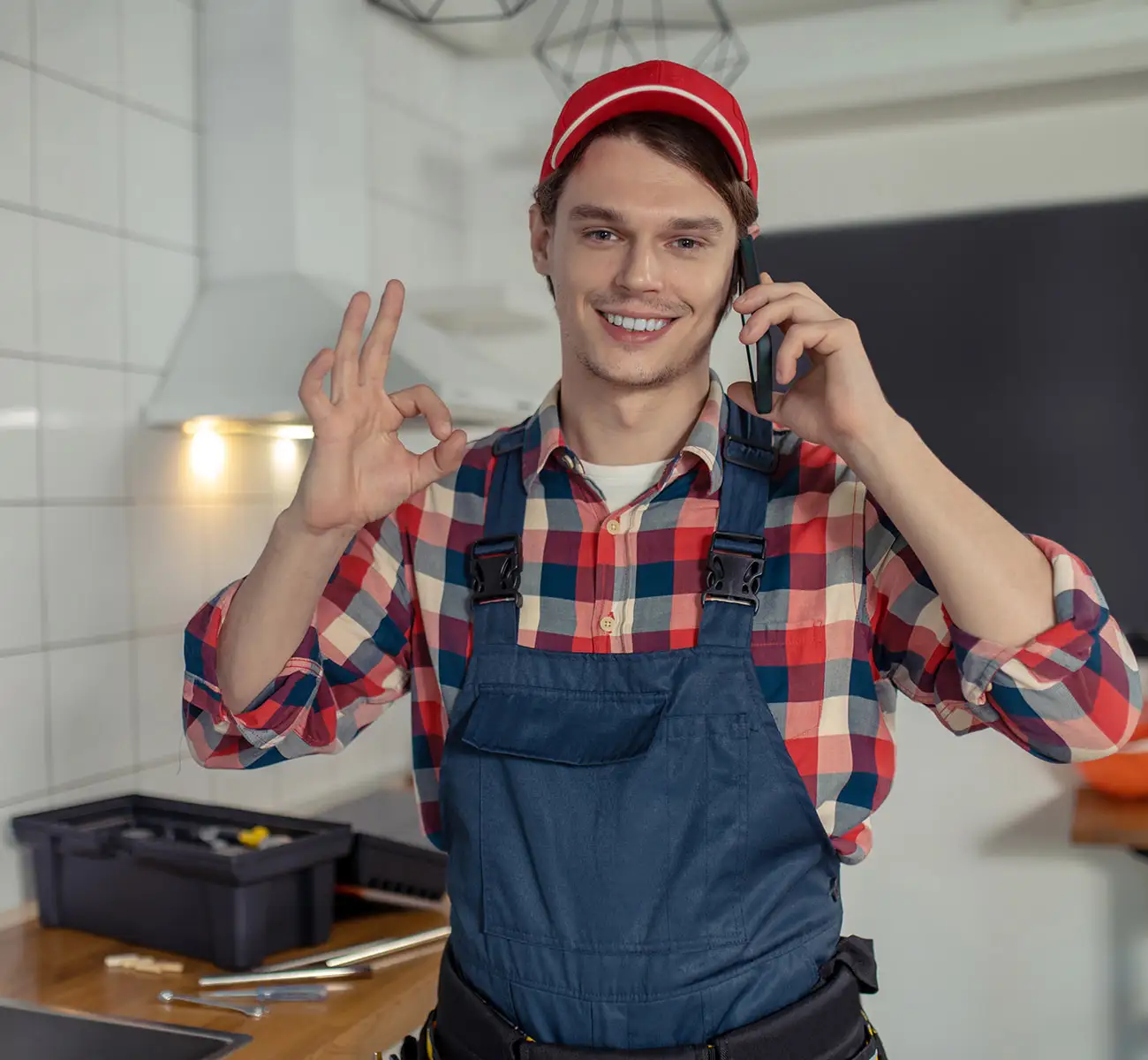 Freundlicher junger Handwerker zeigt das OK-Zeichen mit der Hand